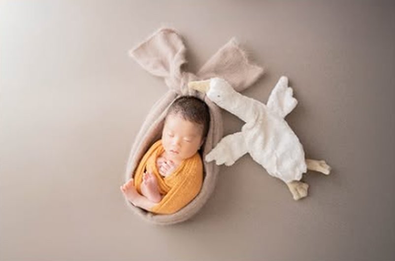 おくるみに包まれて眠る赤ちゃんのニューボーンフォト